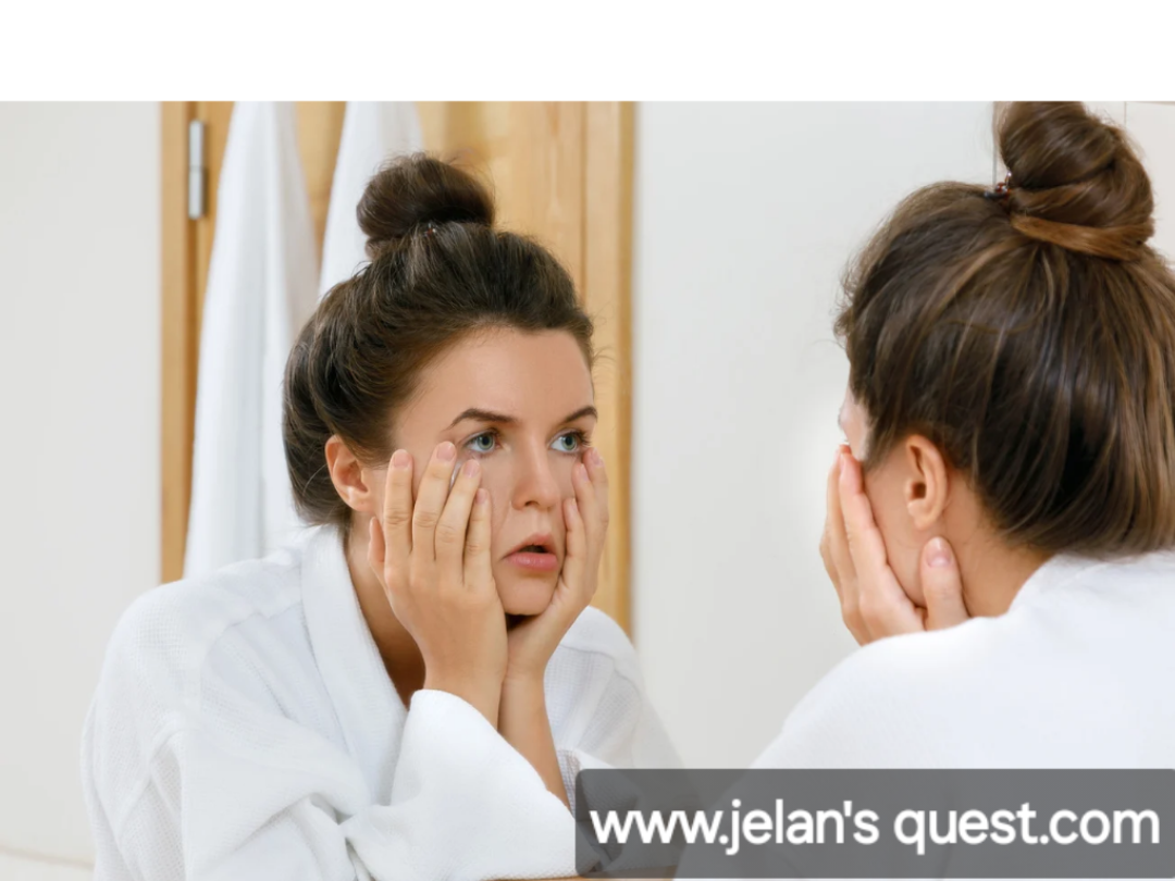 A-tird-mom-standing-in-front-of-a-mirror-wearing-a-white-robe-has-her-tired-up-in-a-messy-bun