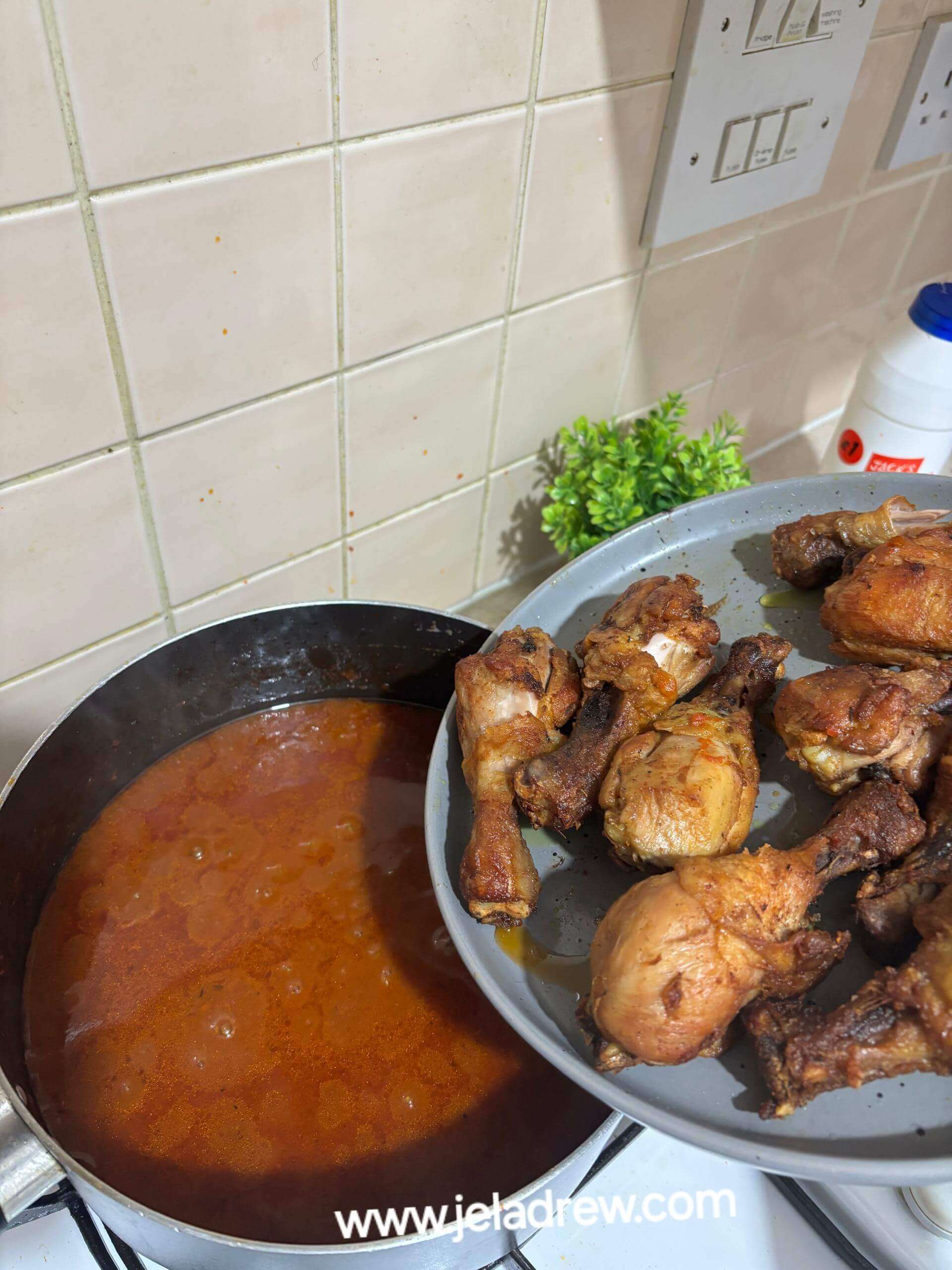 A-pot-of-stew-simmering-on-a-gas-beside-a-plate-of-chicken-and-fish-ready-to-be-added-to-the-stew