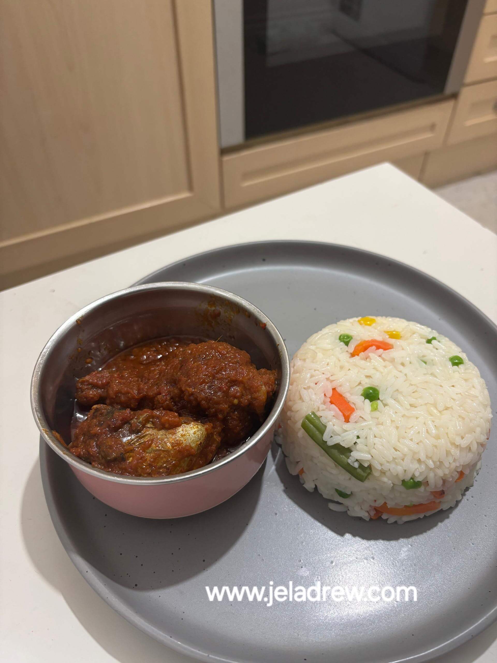 Nigerian-stew-served-with-white-rice-and-vegetable-on-a-gray-plate