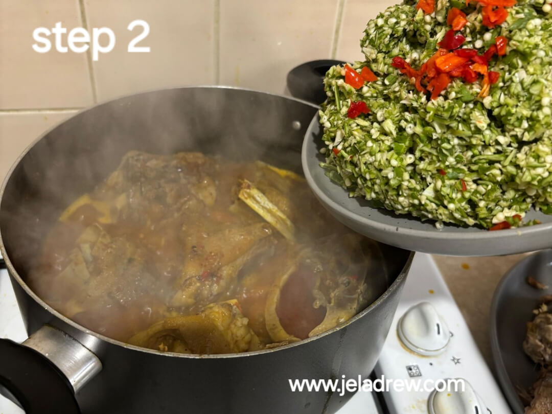 Freshly-chopped-and-okro-being-added-to-a pot-of-boiling-soup-with-fish-and-meat 