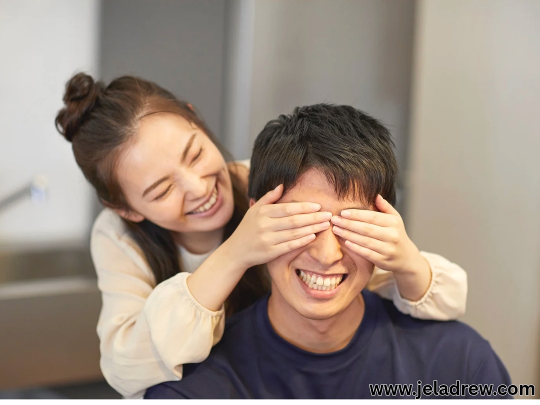 -Wife-playfully-surprising-her-husband-by-covering-his-eyes-with-her-hands-both-smiling
