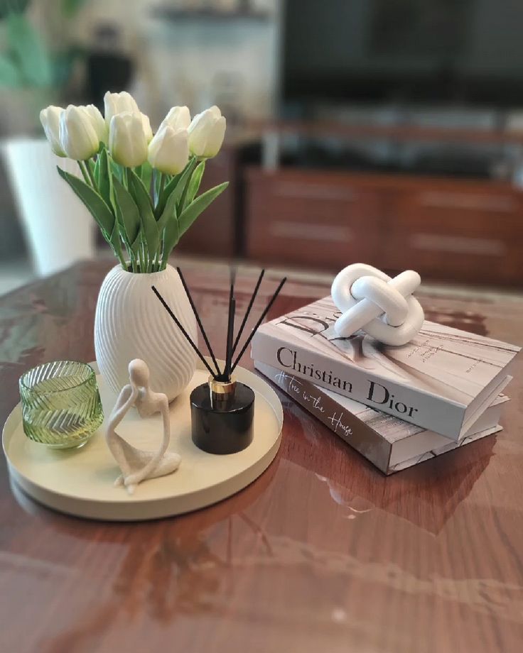 Glass-coffee-table-with-a-tray-vase-of-tulips-candle-diffuser-and-stacked-books-10 easy-winter-decor-ideas-for-your-coffee-table