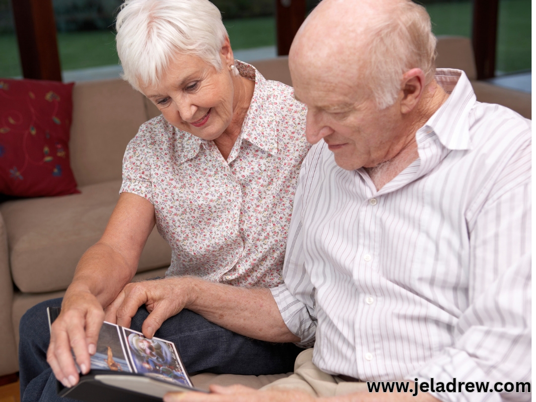 Elderly-couple-sitting together-on-a-couch-smiling-as-they-look-through-an-old-photo-album-celebrating-years of-love-and-memories