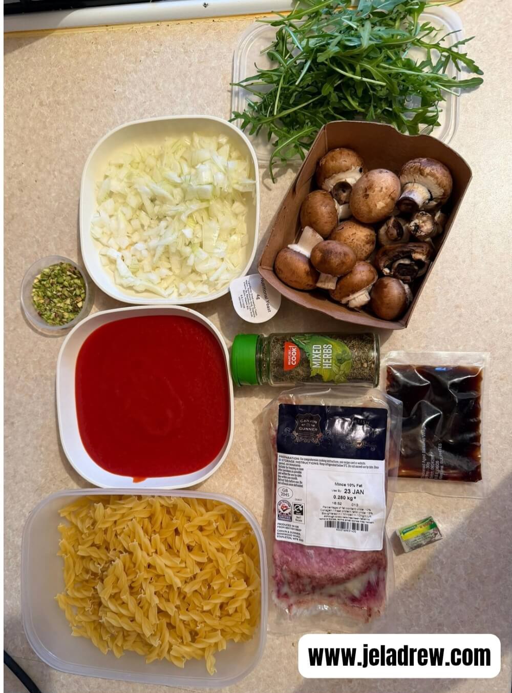 Fresh-ingredients-for-home-made-beef-ragu-pasta-including-mush-rooms-minced-beef-tomato-sauce-fusilli-pasta-onions-garlic-herbs-and-rocket-leaves.