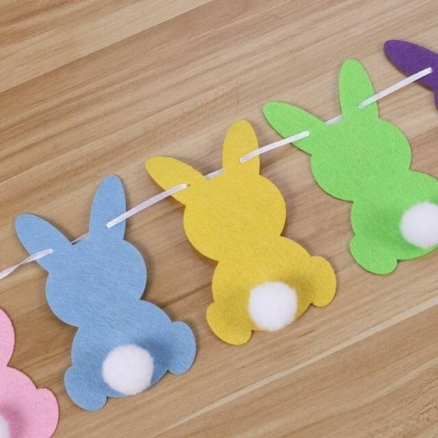 Pastel-paper-bunny-garland-with-white-pom-pom-tails-on-wooden-surface-easy-easter-decor