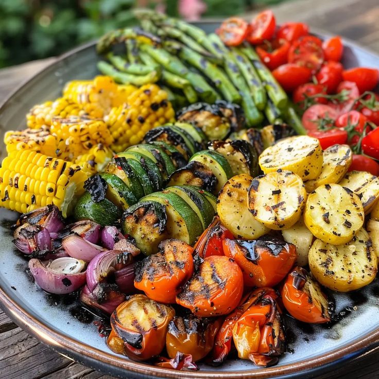 Large-dark-ceramic-serving-platter-piled-with-a-colorful-grilled-vegetable-medley-including-charred-zucchini-rounds-corn-on-the-cob-pieces-grilled-asparagus-spears-red-onions-yellow-squash-and-blistered-tomatoes 